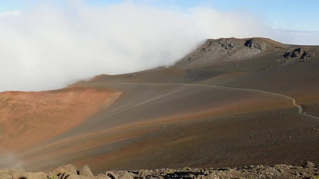 A panning view of the landscape, clouds, and hiking trail at the top of Haleakala volcano in Maui, Hawaii
