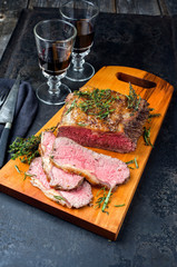 Traditional Commonwealth Sunday roast with sliced cold cuts roast beef with herbs and red wine as closeup on a modern design cutting board