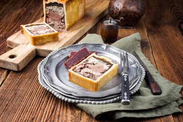 Traditional French Pate en croute with goose meat and liver ofered with quince cheese as closeup on...