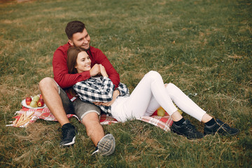 Cute couple in a park. Pair sitting on a blanket. Guy in a red shirt