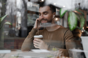 Bearded man drink coffee, keeps eyes closed, sitting at the workplace, relaxing finished work, happy professional employee enjoy success rest from computer feeling stress relief peace of mind