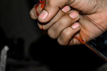 a serial killer is holding a sharp broken bloody glass in the darkness 