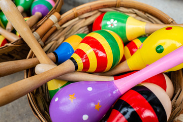 Colorful wooden rattles in a basket on the market for handmade souvenirs in Tryavna, Bulgaria. Maracas for baby toy musical instrument, learning and education concept.