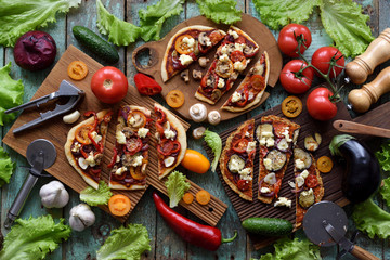 Healthy vegetarian pizza party concept. Flat lay of keto cauliflower and dough pizzas with...