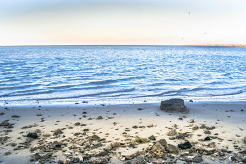 breathtaking view of sandy beach and rocks with sea and sky in the background 