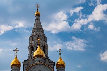 Fototapeta na wymiar Golden domes and bell tower of the Orthodox Church on a background of cloudy sky