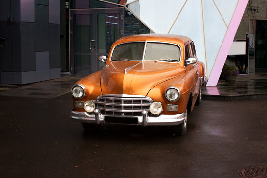 Old orange car after rain on asphalt