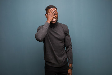 young african american black man laughing and slapping forehead like saying d‚Äôoh! I forgot or...