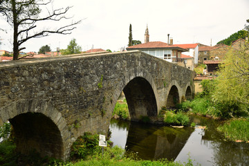 Fototapeta premium Ancient medieval stone bridge on the Camino de Santiago, the Compostela pilgrimage thru-hike, Galicia, Northern Spain (Spring)