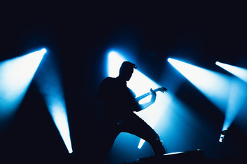 Guitarist plays solo. silhouette of guitar player in action on music stage. popular music rock band...