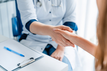 Close up of female medicine doctor shaking hands with patient
