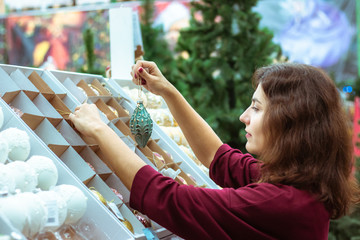 Obraz premium Young woman choosing toys at Christmas market. Winter holidays concept.