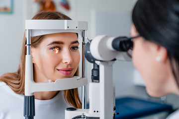 Eye doctor with female patient during an examination in modern clinic - obrazy, fototapety, plakaty