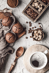 Coffee beans with coffee and muffins on grey textured background.