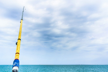 a hunter is fishing at the beach by a fishing stick in bright and beautiful sunny day