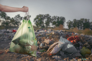 Landfill in the nature. Hand with trash bag.