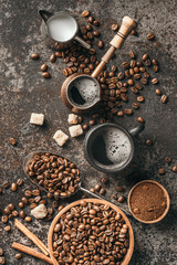 Coffee cup, sugar, milk and coffee beans on dark background.