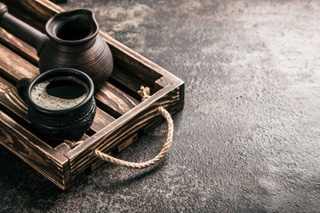 Coffee on wooden tray with coffee beans on dark textured background. Top view with copy space. Background with free text space.