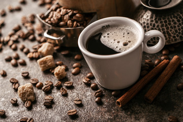 Coffee cup and coffee beans on dark stone background.