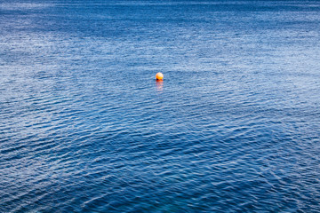 Small red buoy on a background of blue water of a large space. View from above. Background. Outdoor