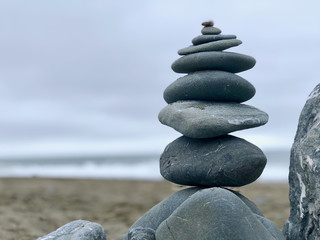 Near ocean a lot of pebbles one above other on sand.