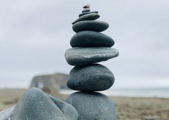 On sand near sea, some gray pebbles one above other.