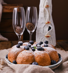 Christmas cake with berries and icing sugar on a wooden background. Traditional pastries in Italy.