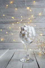 Marshmallow in a glass on a background of light boards and bokeh of lights