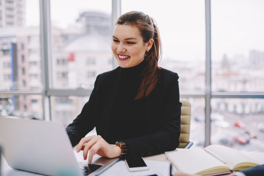 Young prosperous female entrepreneur dressed in formal wear working at modern leptop device with wireless 4G internet.Successful businesswoman checking database online on modern netbook in office