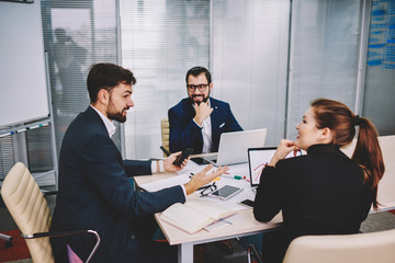 Team of successful professionals together with experienced proud ceo collaborating on discussion of creative ideas and productive business plan during briefing sitting at meeting table in office
