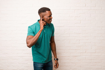 young african american black man looking serious and curious, listening, trying to hear a secret...