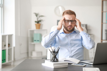 Obraz premium Young man suffering from headache in office
