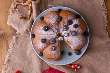Obraz na płótnie Canvas Christmas cake with berries and icing sugar on a wooden background. Traditional pastries in Italy. Above