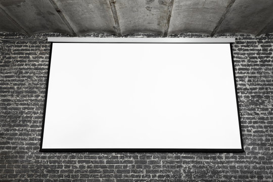 Image of white projector screen on grey brick wall.