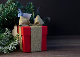 gift red box with a gold ribbon on the background of the Christmas tree