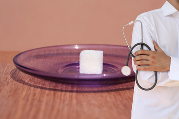 dietitian doctor in white uniform with a stethoscope in his hands, followed by one white cube of...