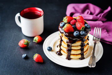 pancakes with chocolate glaze, strawberries, blueberries and raspberries