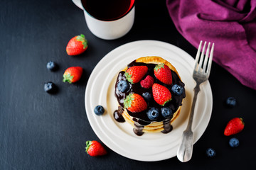 pancakes with chocolate glaze, strawberries, blueberries and raspberries