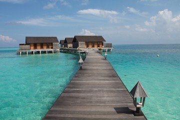 Fototapeta premium jetty on the sea with water villas bungalows at the end of a wooden walkway, Maldives 