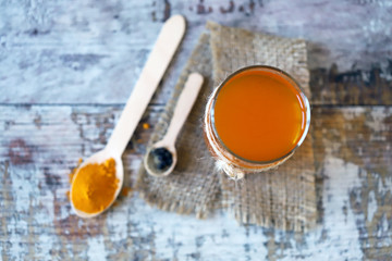 Warm water with turmeric in a glass. Turmeric and black pepper. Selective focus. Macro. Golden water.