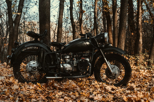 Black old russian motorbike K 750 in autumn wood. Close up