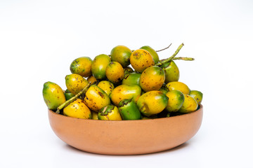 Pottery bowl with ripe and delicious pupunha palm fruit (Bactris gasipaes), harvested from the Amazon rainforest, isolated on white background. Concept of healthy eating, health, cooking and nature.