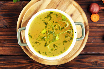 Broth with carrots, onions various fresh vegetables in a pot - colorful fresh clear spring soup. Rural kitchen scenery vegetarian bouillon stock