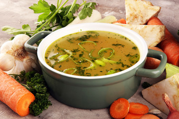 Broth with carrots, onions various fresh vegetables in a pot - colorful fresh clear spring soup....