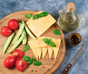 .cheese, tomatoes and cucumbers on a wooden board