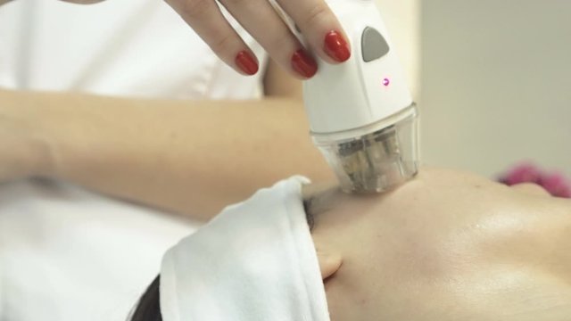 Young woman undergoing procedure of rf lifting in beauty salon, close up