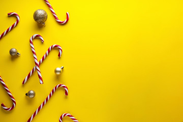 Christmas concept. Christmas candies with golden toys on a yellow background. Flat lay, place for text.