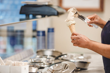Worker puts Italian ice cream cone in horn with chocolate - obrazy, fototapety, plakaty