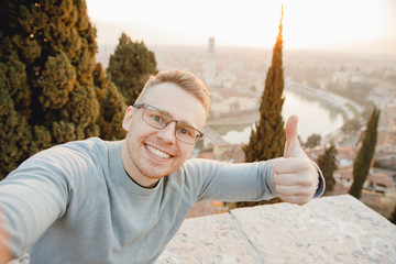 Happy man traveler taking selfie photo on city background Verona Italy sunset. Travel concept