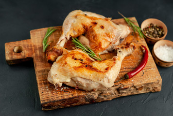 Two fried chicken legs on a stone background with spices, ready to eat